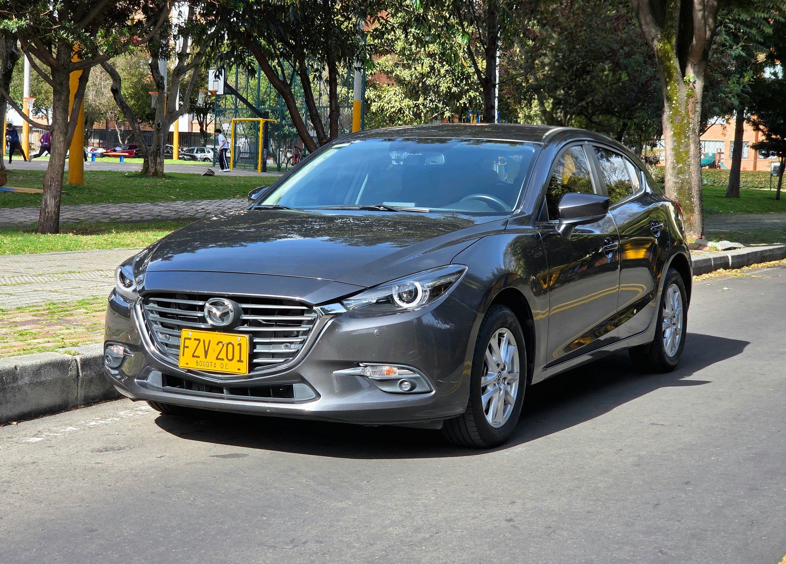 Mazda 3 2020 usado gris oscuro vista frontal lateral estacionado parque Bogotá